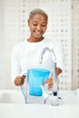 Water, filter and black woman at tap with jug for liquid purification, cold hydration and cooling bottle at home. Happy