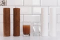 Water filter cartridge used and a glass of dirty water and new pure filter with a glass of clean water from domestic osmosis Royalty Free Stock Photo