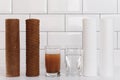 Water filter cartridge used and a glass of dirty water and new pure filter with a glass of clean water from domestic osmosis Royalty Free Stock Photo