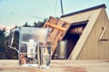 Water filter jug and a transparent glass cup of clean water in front of wooden draw well outdoors in summer evening