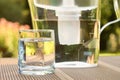 Water filter pitcher and a clean glass of a clear water close up on the summer garden background Royalty Free Stock Photo