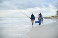 Water, fishing and men walking on beach together with cooler, tackle box and holiday conversation. Ocean, fisherman and Royalty Free Stock Photo