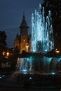 Water flowing from an artesian fountain decorated with colorful lights and a cathedral in the background. Royalty Free Stock Photo