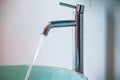 Water flowing from faucet to green washbasin, Bathroom concept