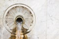 Water flowing from an old italian brass fountain and marble with floral shapes - image with copy space Royalty Free Stock Photo