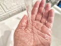 Water Flowing Onto an Open Hand in a Sink. detailed view of a stream of clear water pouring down onto the palm of a hand