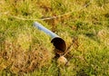 Water flowing out of a drain pipe in a field Royalty Free Stock Photo