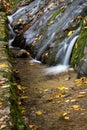 Water flowing over rocks into spillway, autumn season with fall leaves Royalty Free Stock Photo