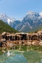 Water is flowing over some rocks of the Blue Moon Valley Lake with the Jade Dragon Snow Mountain in Yunnan, China in the backgroun Royalty Free Stock Photo