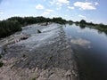 Water flows through the dam of Mygiivska HPP. Rapids and river dam on the Southern Bug. Group of people resting on the river water Royalty Free Stock Photo