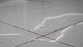 Water flows on floor covering white ceramic tile in bathroom