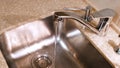 Water flows from the kitchen faucet into the metal sink. Concept. Clean water flowing from a chrome tap in the kitchen. Royalty Free Stock Photo