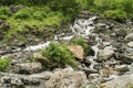 Water flows over rocks at the bottom of a mountain waterfall Royalty Free Stock Photo