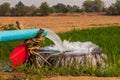 Water flows from pipes into a basin in rice fields near arid soil Royalty Free Stock Photo