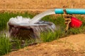 Water flows from pipes into a basin in rice fields near arid soil Royalty Free Stock Photo