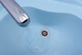 Water flows from the tap in a blue washbasin Royalty Free Stock Photo