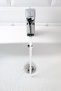 Water flows from the tap into white ceramic sink and white tile wall, vertical. Modern bathroom Royalty Free Stock Photo