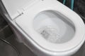Water flushing in toilet bowl. White hanging toilet seat on white toilet in the home bathroom with grey tiles in Royalty Free Stock Photo