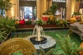 A water fountain and pool surrounded by lush green trees and plants, gold coins and colorful flowers, Chinese lanterns