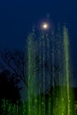 Green lit fountain, touching the Full moon on the sky