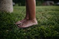 Water from a garden hose, from well splashes onto boy& x27;s bare fee. Close-up of feet standing on grass with water Royalty Free Stock Photo