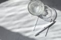 Water glass, blank notebook mockup, pen on white marble table background with natural dappled light shadow. Minimalist aesthetic