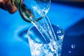 Water glass, pouring water, blue background, splashes