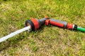 A water gun with a hose lies on the grass in the garden, a water sprinkler for watering plants Royalty Free Stock Photo