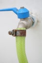 Water hose with rusty tightener with blue handle on white wall Royalty Free Stock Photo