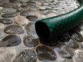 water hose on a wet floor patterned with small stones small rough