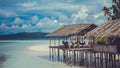 Water Hut of Homestay on Sandy Bank, Clouds in Background - Kri Island. Raja Ampat, Indonesia, West Papua