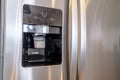 Water and ice dispenser on the shiny door of a refrigerator inside a home Royalty Free Stock Photo