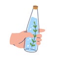 Water infused with rosemary leaf. Holding aromatic fresh aqua bottle in hand. Refreshing summer detox drink, refreshment