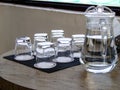 Water in the jar and row of clean glasses on the table Royalty Free Stock Photo