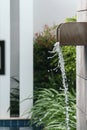 Water jet falling into the swimming pool. Swimming pool surrounded of palm trees in the yard of villa. Royalty Free Stock Photo