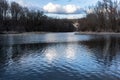 Water landscape in riparian forest with reflection of big gray and white clouds in the glittering water Royalty Free Stock Photo