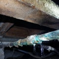 Water leak in corroded copper water pipe in the plumbing under a traditional villa in New Zealand Royalty Free Stock Photo