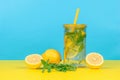 Water with lemon and mint in a glass on a yellow and blue background Royalty Free Stock Photo