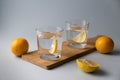 Water with lemon in two glasses on a wooden stand on a light blue background Royalty Free Stock Photo