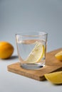 Water with lemon in two glasses on a wooden stand on a light blue background Royalty Free Stock Photo