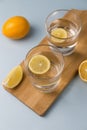 Water with lemon in two glasses on a wooden stand on a light blue background Royalty Free Stock Photo