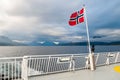 Norwegian flag on a ferry in the fjord. Sea with mountains in the background. Royalty Free Stock Photo