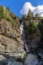 Water of Lillaz waterfall Cascate di Lillaz falling over granite rocks forms small karst pool under blue sky, Cogne, Aosta