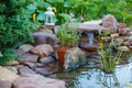 Beautiful artificial pond for growing koi carps in the garden near the house. There are a lot of green plants around, a Royalty Free Stock Photo