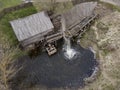 Water mill wheel rotates under a stream of water. Traditional village machinery, aerial view Royalty Free Stock Photo