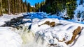 Water of the Murtle River tumbles over the edge of the partly frozen Mushbowl Falls in the Cariboo Mountains of Wells Gray