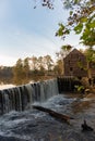 Water overflows from a pond at the historic Yates Mill in Wake County, North Carolina at dusk in autumn with trees reflecting in Royalty Free Stock Photo