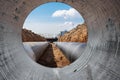 Water pipes for drinking water supply lie on the construction site. View from a large concrete pipe. Preparation for earthworks