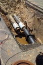 Water pipes in ground pit trench ditch during plumbing under construction repairing. Repair of a water supply or gas pipeline Royalty Free Stock Photo