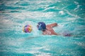 Water polo player swimming in a pool after a ball splashing water Royalty Free Stock Photo